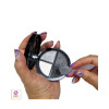 A hand holding an eye shadow compact and the other hand is holding a cosmetic spatulas lucite angled makeup mixing tool