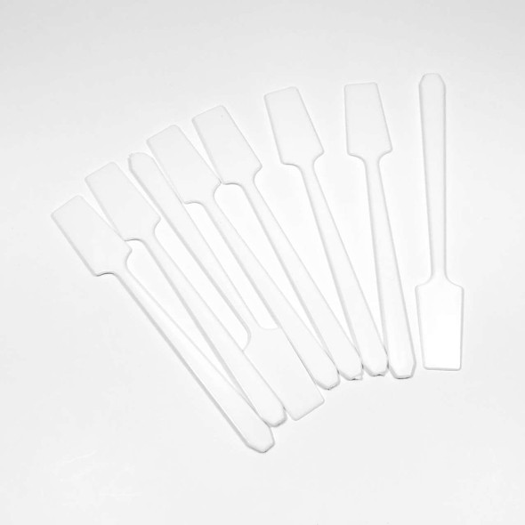 A bunch of white plastic long handle cosmetic spatulas