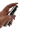 A finger pressing the pump of a high-end silver pump bottle for skincare products