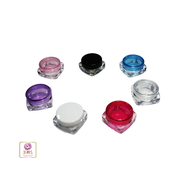 Seven small square cosmetic jars with lid colors of purple, pink, black, blue, clear red, and white